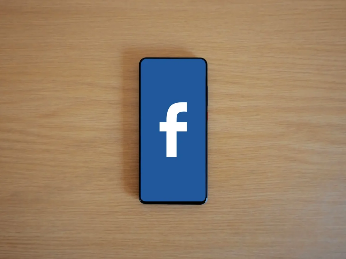Phone showing the Facebook logo on a wooden table