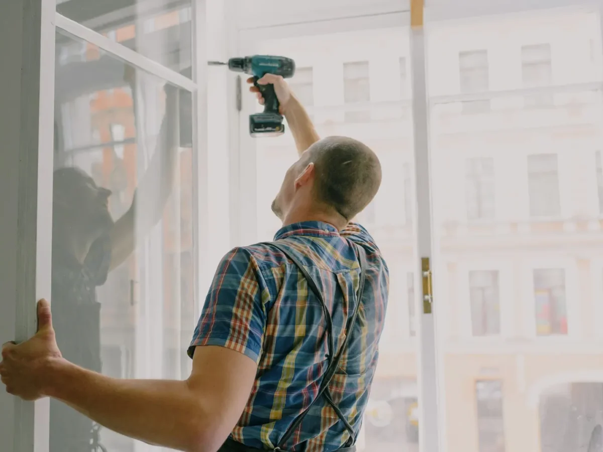 Handyman fitting a window frame with a cordless drill