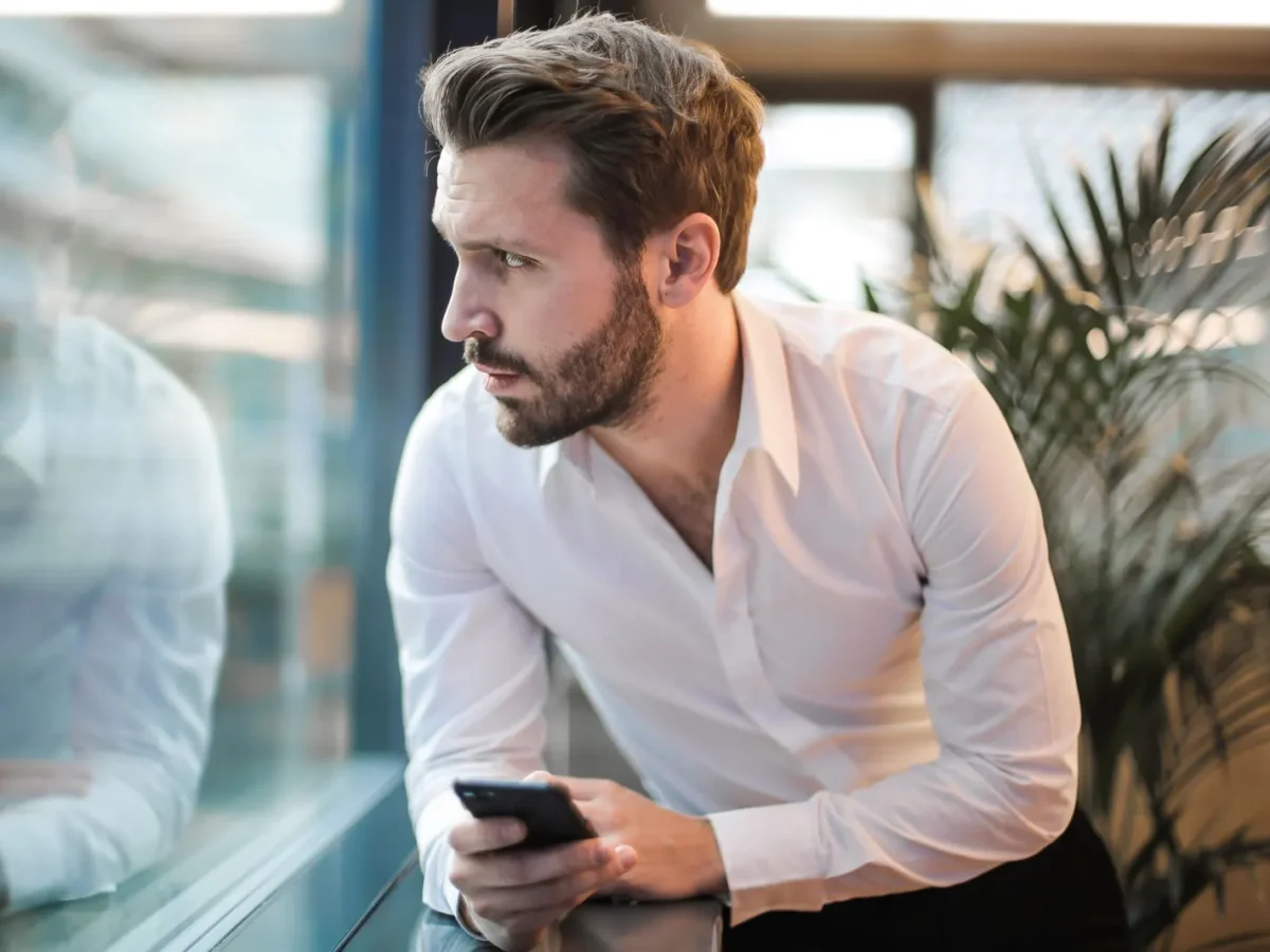 Business owner looking at his phone by an office window