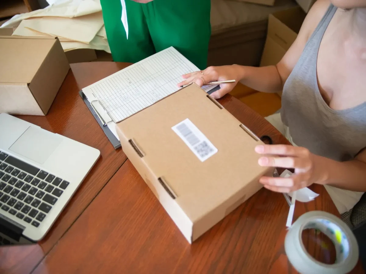 Small business owner packing an online order next to a laptop