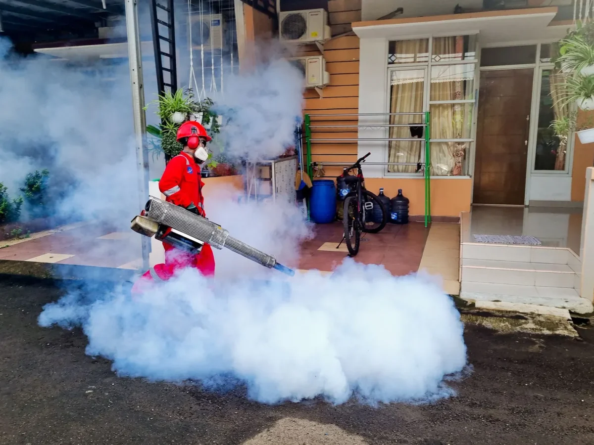 Pest control technician fogging outside a house