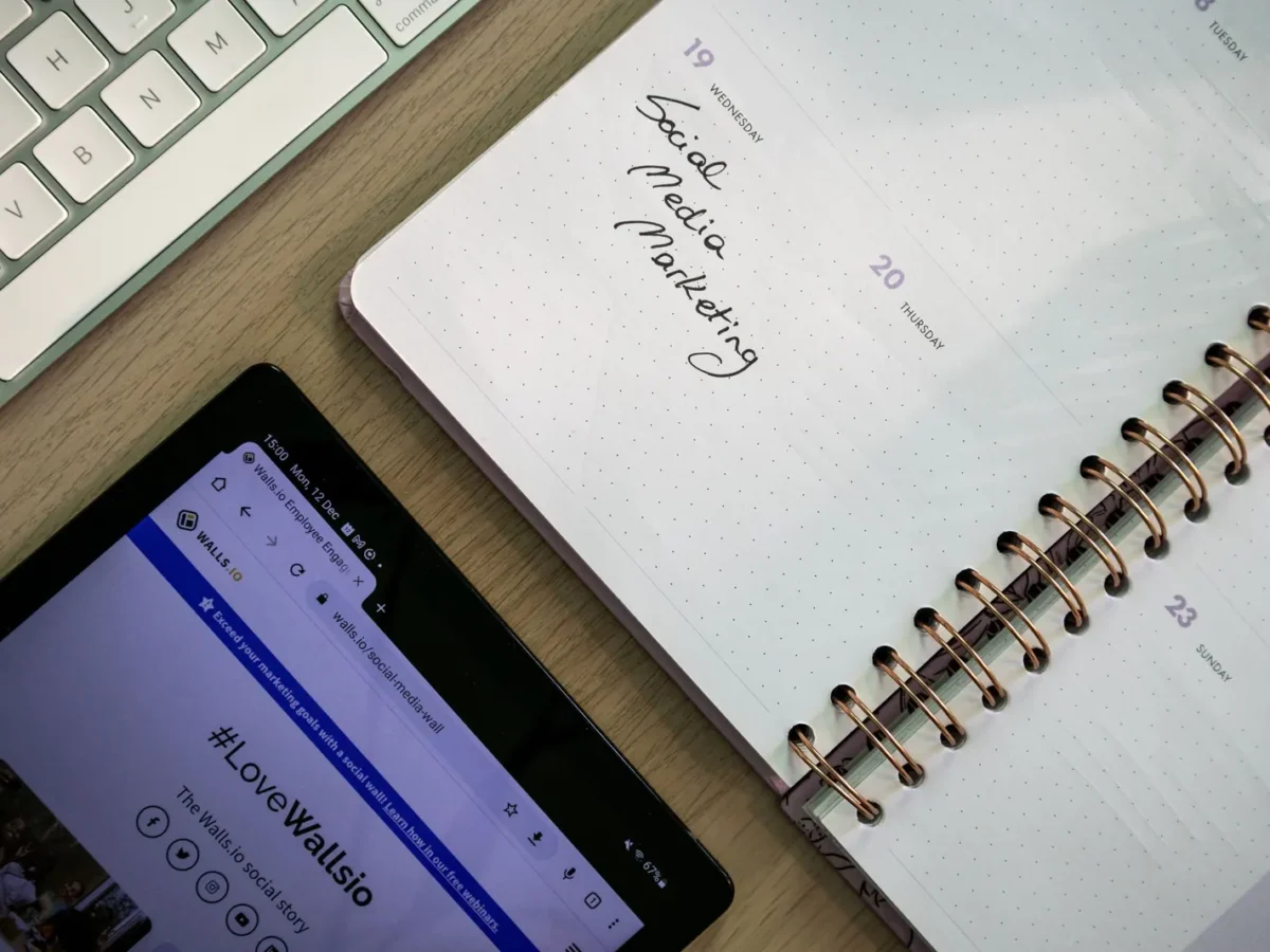 Social media marketing plan in a notebook beside a tablet