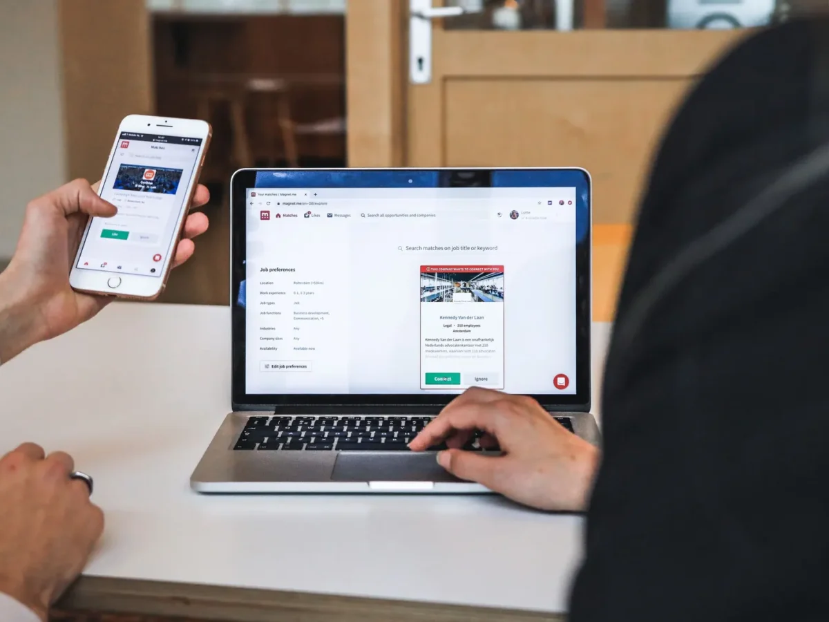 Person checking a website on a phone and a laptop
